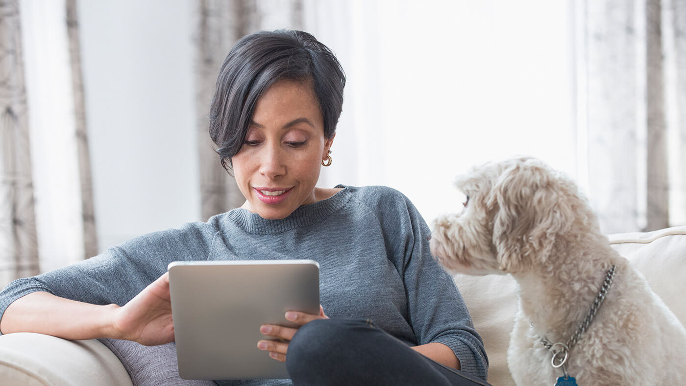 woman using tablet as dog watches